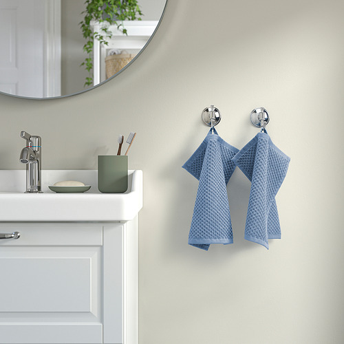 Baño moderno con paredes grises, tocador blanco, grifería cromada, espejo y toallas GULVIAL azules en ganchos.