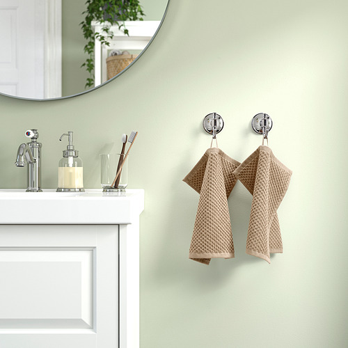 Las toallas GULVIAL beige cuelgan de ganchos cromados junto al lavabo del baño con espejo.