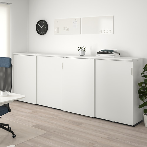 Mueble de oficina GALANT blanco con puertas correderas, plantas, libros, silla azul, suelo de madera.