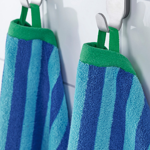 Dos toallas a rayas cuelgan una al lado de la otra en ganchos blancos: rayas azules y celestes con ribetes verdes, mostrando su absorbencia y coordinación de colores.