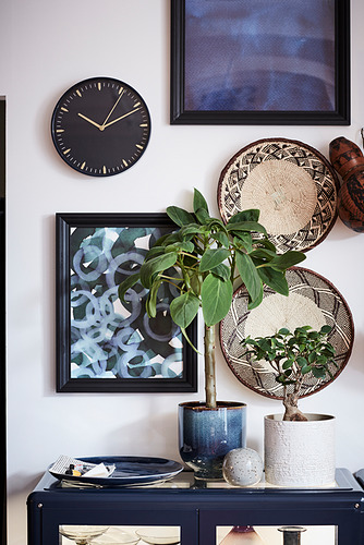 Decoración moderna: reloj negro, plantas, arte, aparador.