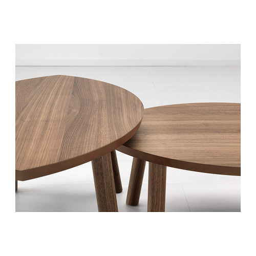 Dos elegantes mesas nido de madera ovaladas con un diseño suave y entrelazado; Cálida veta de madera natural visible.