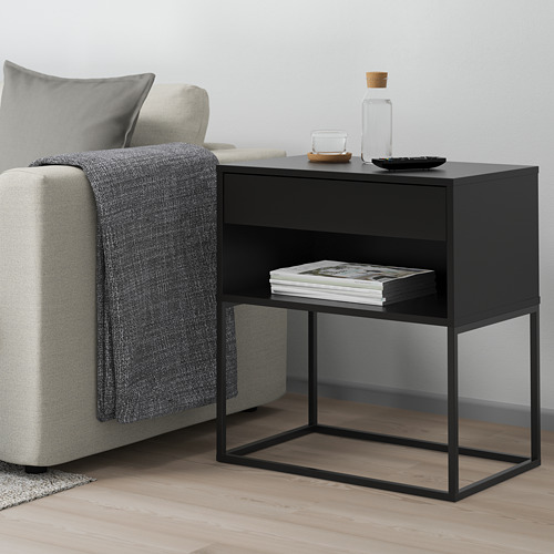 Mesa auxiliar negra con 2 estantes, junto al sofá, sostiene revistas, minimalista.