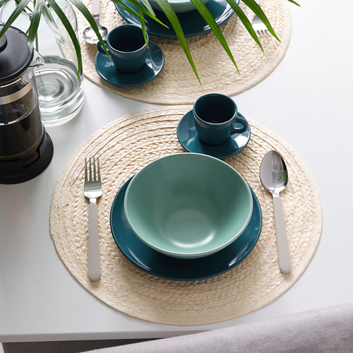 Una mesa con cuencos, tazas y manteles individuales tejidos de FÄRGKLAR verde. Incluye cubiertos y una prensa de café.