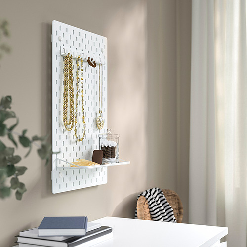 Organizador SKÅDIS de pared con ganchos y estante que sostiene collares, colgantes y un tarro.