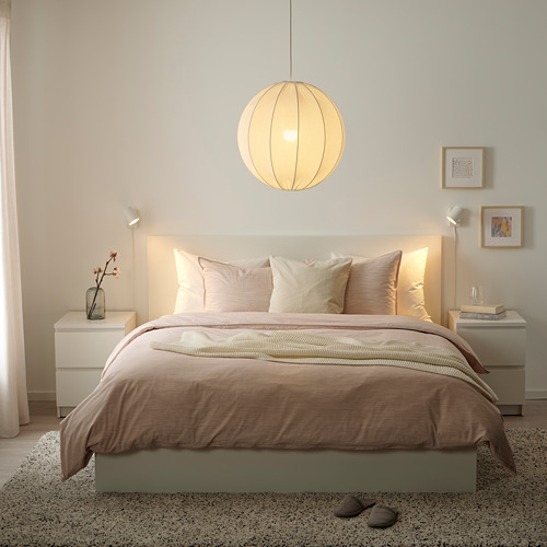 Dormitorio moderno con lámpara REGNSKUR, ropa de cama beige, mesitas de noche y decoración minimalista.