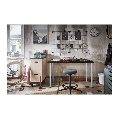 Área de trabajo de estilo industrial con escritorio, silla, herramientas y decoración contra una pared rústica.