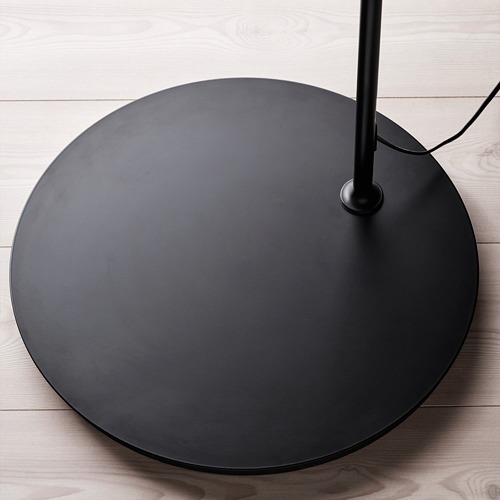 Base de lámpara de pie redonda negra con acabado liso y diseño circular sobre suelo de madera.