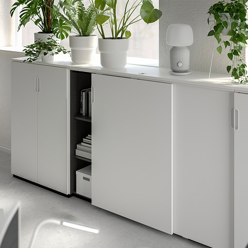Mueble de almacenaje GALANT blanco con libros, caja, lámpara, plantas.
