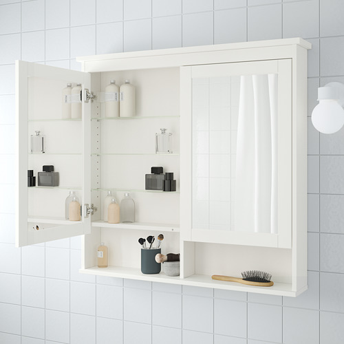 Mueble de baño blanco, abierto con estantes de vidrio que contienen botellas, frascos, brochas de maquillaje y un cepillo para el cabello.