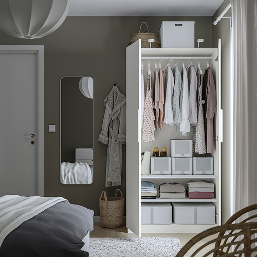 Bedroom with open closet showing clothes, folded clothes, and storage boxes, against dark wall.