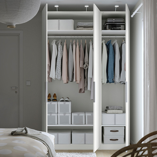 A modern, white, open closet displaying clothes and storage solutions, with socks on shelves and boxes for organization.