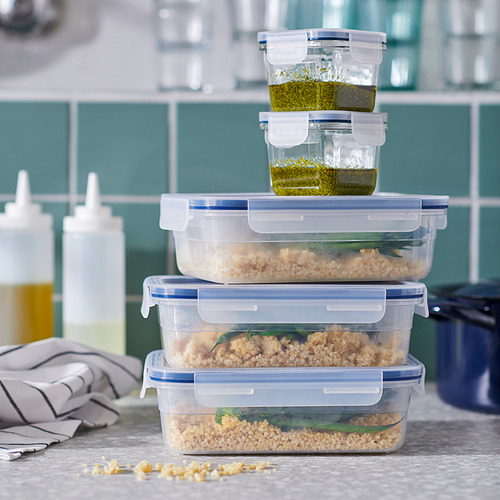 Recipientes de plástico transparente IKEA 365+ apilados con tapas azules, llenos de granos y hierbas, en la cocina.