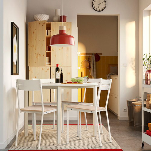 Moderna silla blanca BUSLÄTT colocada alrededor de una pequeña mesa de comedor con mueble de madera al fondo.