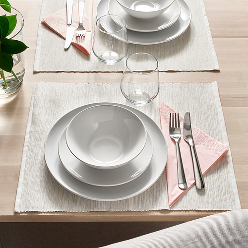 Dos cubiertos de vajilla blanca sobre manteles individuales con servilletas, vasos y utensilios rosas sobre una mesa de madera.