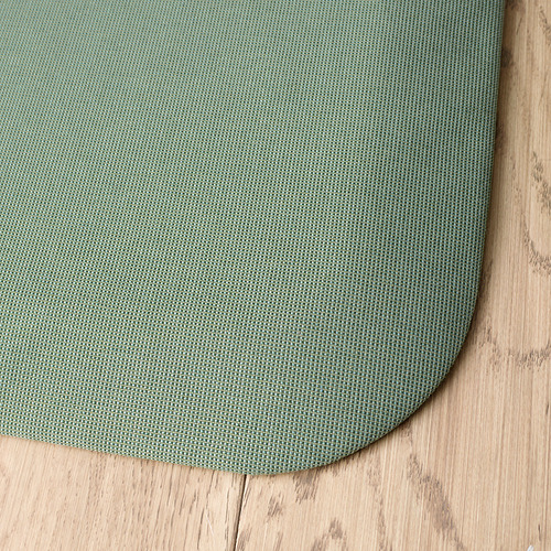 Alfombrilla redonda verde antifatiga sobre suelo de madera, que muestra una textura de calidad y una construcción duradera.