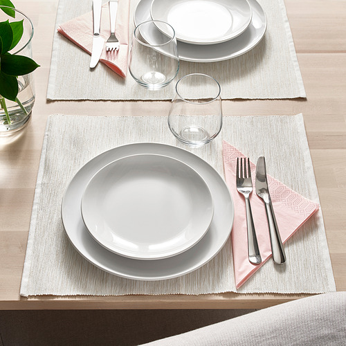 Dos cubiertos con platos blancos, vasos, cubiertos en manteles individuales tejidos para una cena elegante.