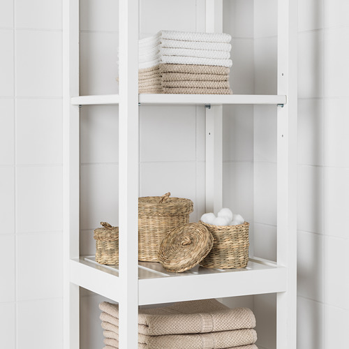 Estantería blanca de baño con toallas cuidadosamente dobladas y cestas tejidas.