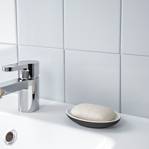 Un lavabo de baño moderno con un grifo cromado y un pequeño plato que contiene jabón.