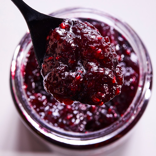 Una cucharada de mermelada de frutos rojos de un frasco de vidrio.