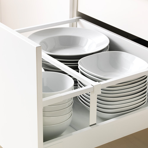 Cajón de cocina abierto con almacenamiento del suelo al techo, con platos y cuencos blancos organizados en compartimentos.