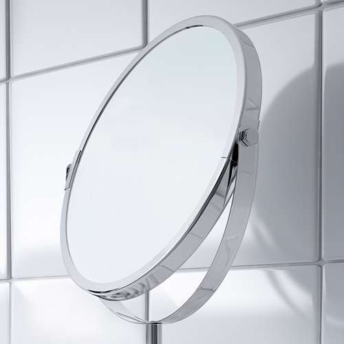 Espejo de tocador redondo cromado, montado en una pared de azulejos, tanto en el lado regular como en el de aumento. Diseño elegante, resistente al agua para uso en el baño.