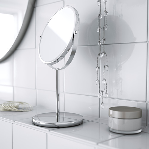 Un elegante espejo de tocador de mesa con base, con un lado de aumento y un lado reflectante regular, ideal para maquillarse o afeitarse.