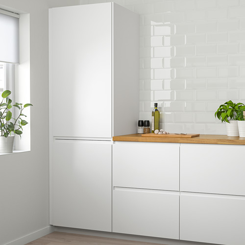 Cocina moderna con gran nevera VOXTORP blanca. Placa para salpicaduras de azulejos, encimera de madera y plantas en macetas.