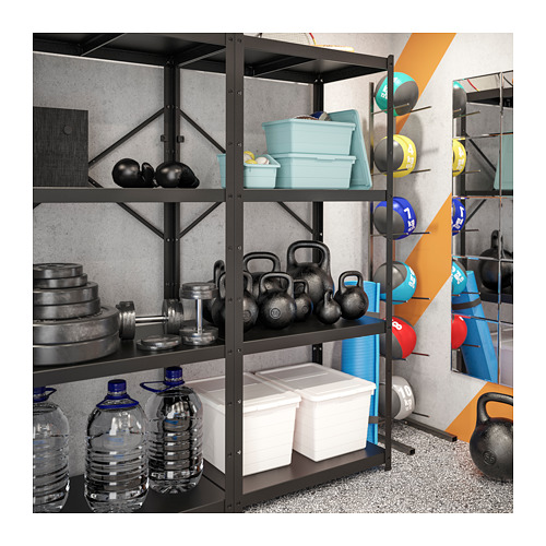 Sistema de estanterías BROR negro para gimnasio en casa que almacena botellas de agua, pesas rusas y recipientes de plástico. El equipo está perfectamente organizado contra la pared gris.