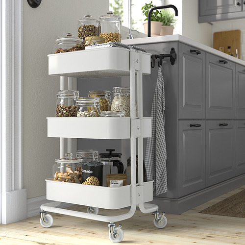 Carro utilitario blanco de Ikea en la cocina, con frascos y suministros, junto a los armarios.