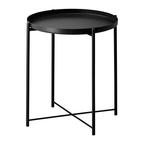 Una mesa de servicio GLADOM circular de color negro con una bandeja extraíble, sostenida por una estructura metálica con patas cruzadas para mayor estabilidad.