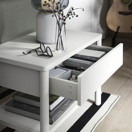 Mesa auxiliar TONSTAD blanca con apertura de cajón, vasos negros, jarrón con flores secas encima, libros debajo.
