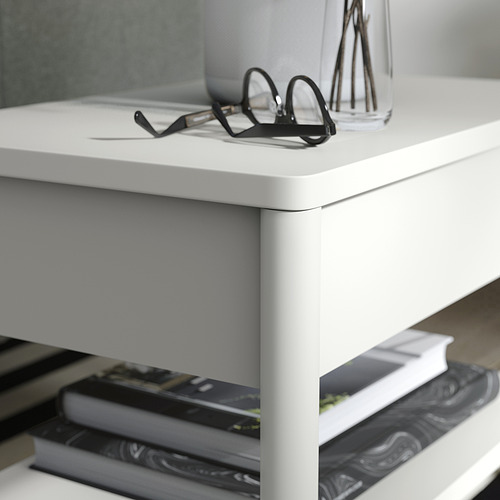 Mesa auxiliar de color blanco roto con cajón, libros y vasos.
