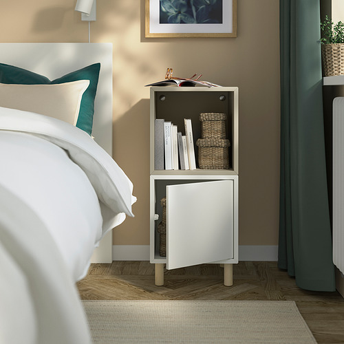 Pequeño mueble blanco de EKET junto a la cama, almacenamiento mixto abierto/cerrado, cabe bajo la ventana.