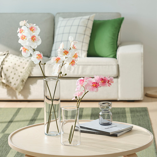 Acogedora sala de estar con sofá blanco, almohadas a cuadros, mesa de café y jarrones.