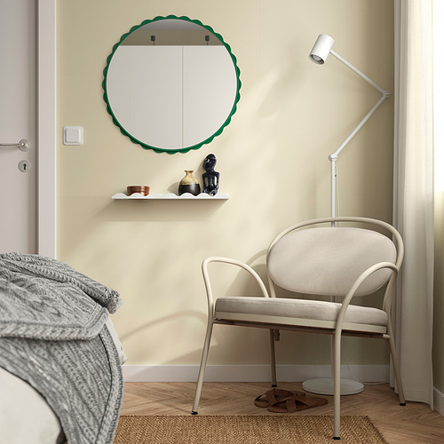 Dormitorio moderno con espejo, silla y lámpara. Espejo redondo verde sobre la estantería, silla blanca junto a la cama.