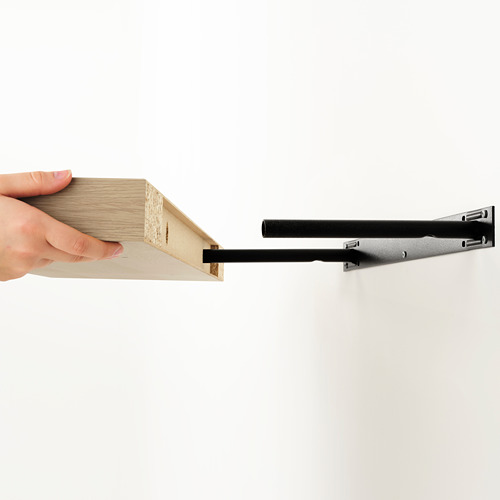 Persona sosteniendo un estante de pared de madera moderno con soportes minimalistas.