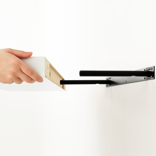 Colocación manual de la caja blanca en el estante de pared negro KALLAX para un almacenamiento seguro.