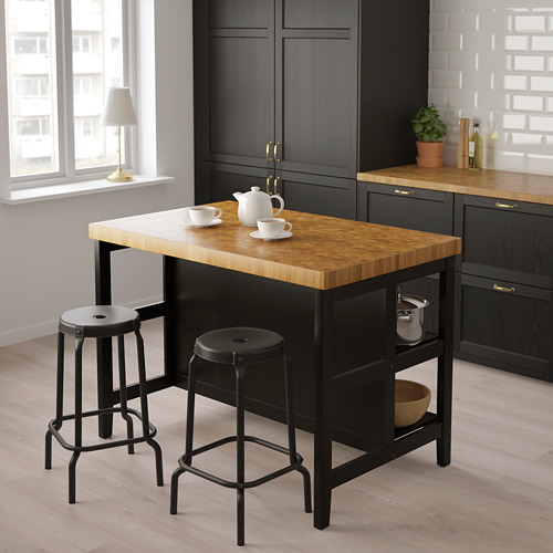 Moderna isla de cocina VADHOLMA con encimera de madera, dos taburetes y tetera con tazas.