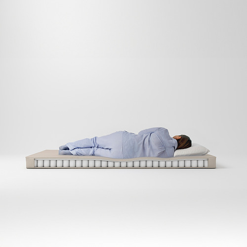 La persona duerme en un colchón VANNAREID, azul, firme, resortes envueltos individualmente, tapa de espuma, asas visibles.
