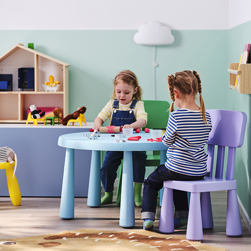 Dos niñas jugando con juguetes en una mesa colorida y liviana con ruedas.