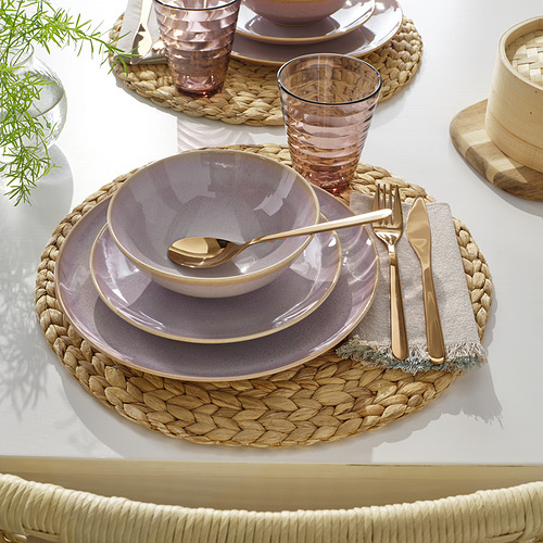 Mesa con platos, tazón, vaso, cubiertos y mantel individual tejido.