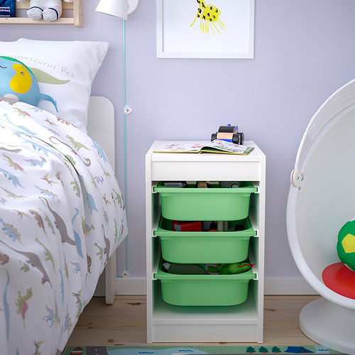 Habitación para niños con almacenamiento TROFAST. Marco blanco, cajas de plástico verde. Junto a una cama y encima de una alfombra.