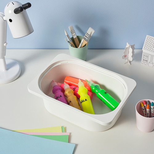 Marcadores de colores en un contenedor blanco de TROFAST sobre un escritorio con materiales de arte, que promueven el almacenamiento organizado y las actividades creativas.