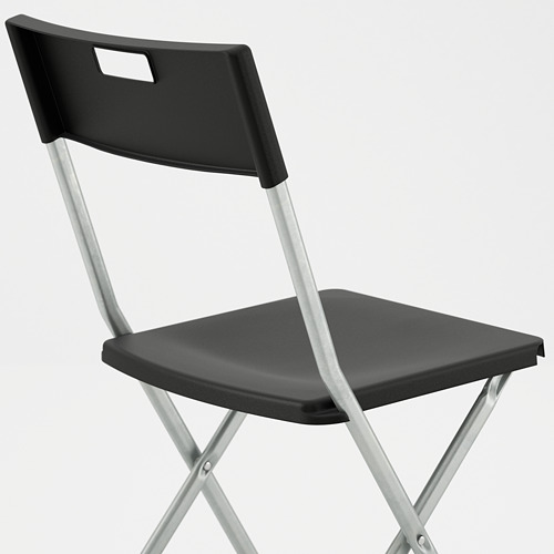 Silla negra con patas metálicas, diseñada para la estabilidad y la portabilidad, un diseño plegable para un fácil almacenamiento.