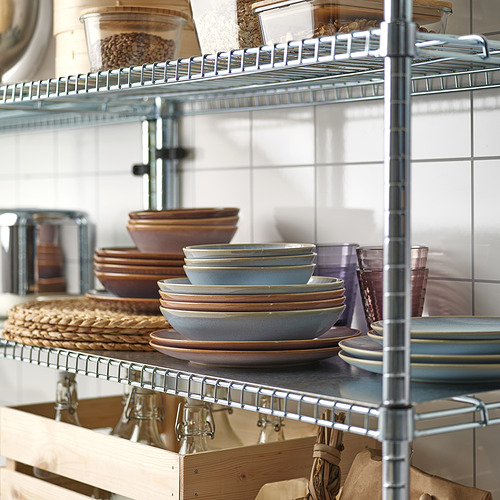 Estanterías de cocina organizadas con estantes metálicos. Platos, tazones, vasos y recipientes de madera de colores apilados.