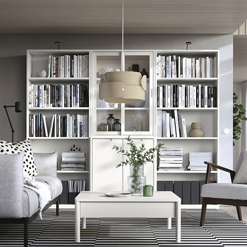 La elegante librería TONSTAD de color blanco roto con puertas de cristal, repleta de libros y decoración, crea una elegancia atemporal.
