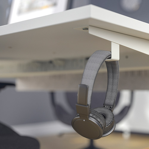 Los auriculares grises cuelgan de un gancho debajo de un escritorio blanco.