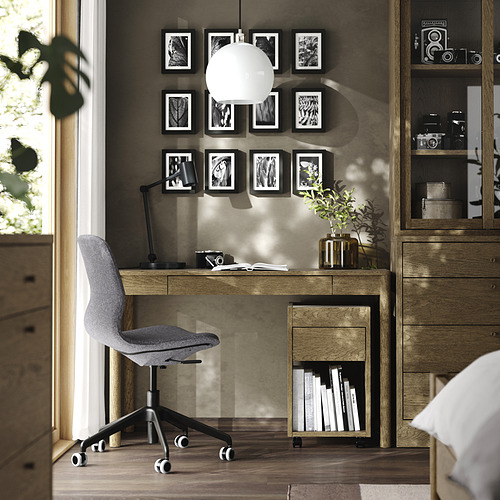 Moderna oficina en casa con escritorio TONSTAD de roble, silla gris, lámpara colgante y arte en la pared.