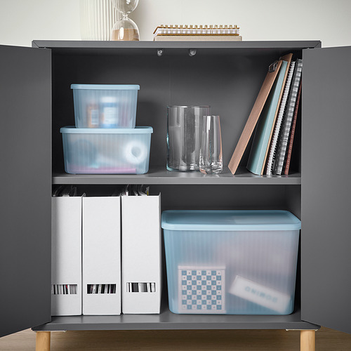 Estantería de cajas de almacenamiento azules y blancas, jarrones transparentes y libros. Las cajas organizan artículos pequeños, son parcialmente recicladas y semitransparentes.